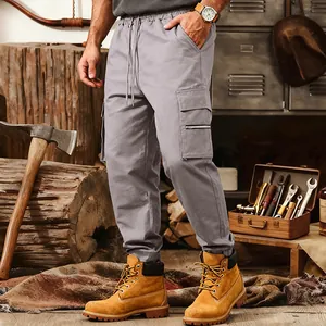 Detail view of men's grey multi-pocket tactical cargo pants in a rugged workshop