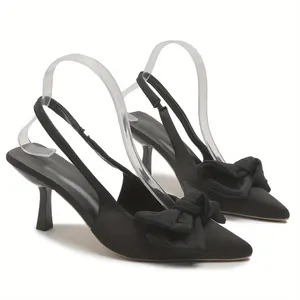 Λεπτομερής πλάγια όψη κομψών μαύρων σατέν slingback γοβών με μεγάλο διακοσμητικό φιόγκο