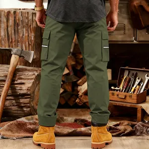 Back view of men's olive green multi-pocket tactical cargo pants shown in a workshop setting