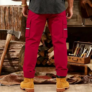 Detail of red tactical cargo pants with side pockets in a rustic workshop setting