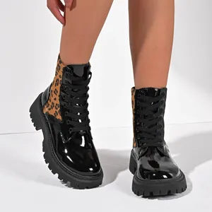 Detail view of stylish leopard print patchwork patent leather boots with thick lug sole