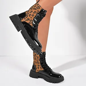 Side view of chic leopard print and black patent leather combat boots with lug soles