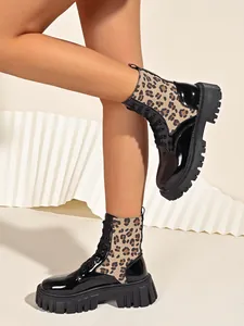 Close-up of leopard print combat boots featuring chunky lug soles and glossy patent leather.