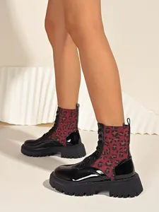 Detail view of women's leopard print Martin boots with black patent leather and thick soles.