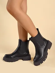 Side view of chic black Chelsea platform boots with chunky lug sole on model