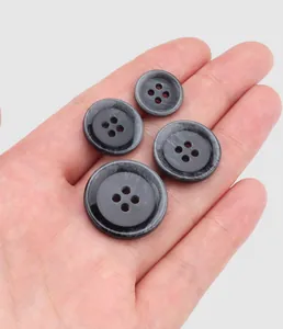 Close-up detail of four different sized grey marbled resin buttons for clothing