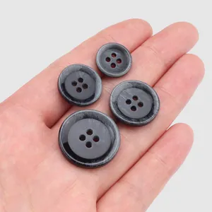 Premium grey resin four-hole buttons for clothing displayed on a hand for scale