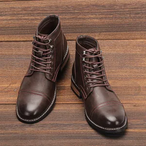 Primer plano de botas de trabajo retro de cuero marrón para hombre en fondo de madera.