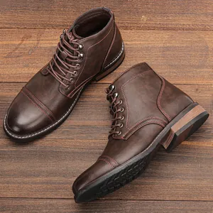 Vista detallada de botas de cuero marrón para hombre con costuras rojas en madera