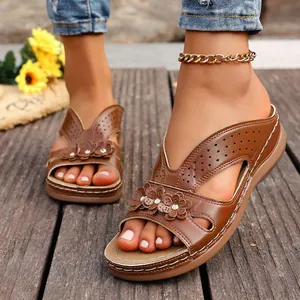 Primer plano de sandalias de cuña en cuero marrón con flores y calados decorativos