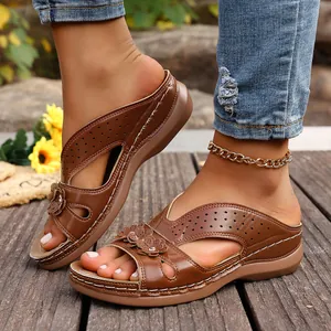 Elegantes sandalias de cuña marrón con detalles florales y diseño de estilo romano.