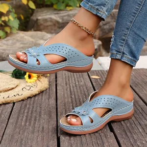 Detalle de sandalias con cuña azules con flores y diseño calado sobre cubierta de madera