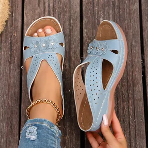 Detalle de sandalias de cuña azul claro con detalles de flores y correas perforadas.
