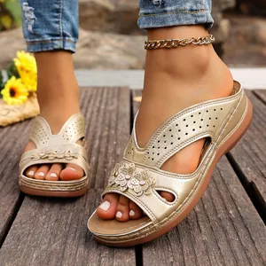 Primer plano de sandalias de cuña doradas con flores y detalles perforados en madera