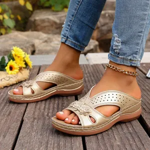 Elegantes sandalias de cuña doradas con detalles florales y diseño perforado en madera