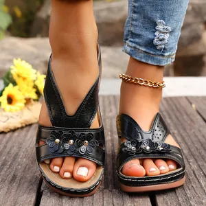 Vista detallada de sandalias de cuña negras con motivos florales y diseño de corte láser