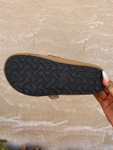 Close-up detail of the non-slip wavy rubber sole on brown suede clog mules for women