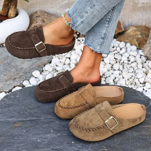 Close-up of fashionable suede mules with adjustable buckle and hand-stitched detailing