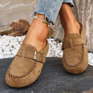 Detail of brown suede clogs with decorative metal buckle and hand-stitched edging