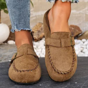 Detail view of brown suede mules featuring a stylish belt buckle and whipstitch trim