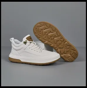 Detail view of white genuine leather men's sneakers with non-slip brown rubber sole.