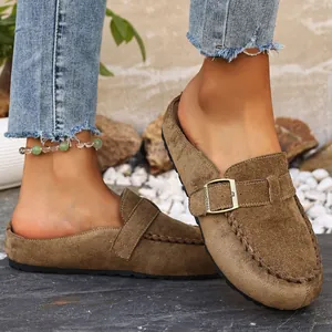 Detail of brown suede closed-toe mules with decorative buckle and hand stitching