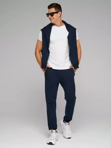 Volledige studio-opname van een mannelijk model in een donkerblauwe joggingbroek en wit T-shirt