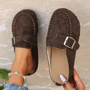 Close-up detail of brown suede Birkenstock-style clogs with gold buckle for women.