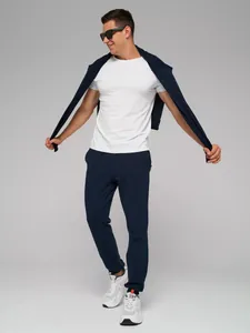 Volledige studiofoto van donkerblauwe joggingbroek voor heren met witte sneakers