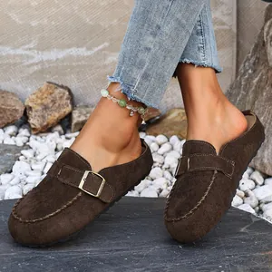 Close-up detail of women's brown suede clogs featuring a stylish bronze buckle