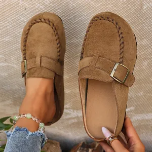 Close-up view of brown suede clogs featuring a stylish buckle and hand-stitched detail