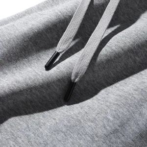 Detail van een grijze joggingbroek met trekkoord en katoen-textuur details.