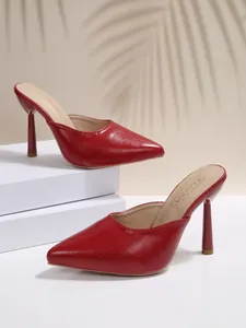 Detail view of elegant red pointed toe high heel mules on a minimalist white platform.