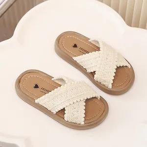 Primer plano de pantuflas de verano para niñas con correas de encaje cruzadas y pompones