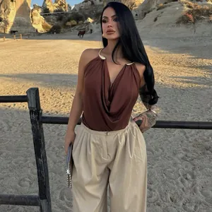 Detailed view of brown metal halter neck cowl neck backless top in outdoor setting