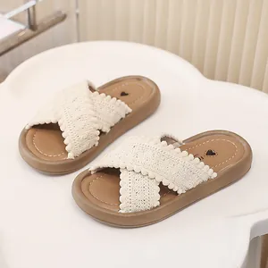 Detalle de la textura de ganchillo y pompones en las sandalias de tiras cruzadas para niñas