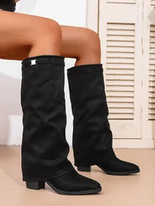 Close-up of black pointed-toe slouchy boots with stylish metal buckle detail