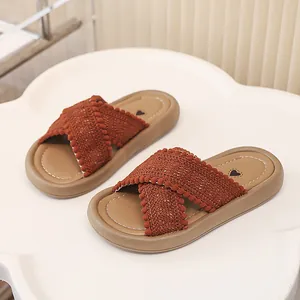 Primer plano de sandalias tejidas para niña con tira cruzada de pompones y corazón