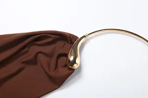 Macro detail of fashionable golden teardrop halter neck ring on coffee brown sleeveless vest