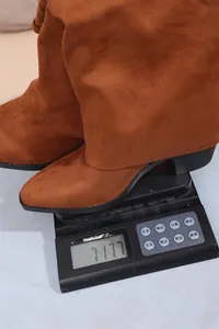 Detail view of brown pointed-toe slouchy boots showing a total weight of 717.7 grams