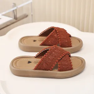 Primer plano de sandalias para niña con tiras de ganchillo marrón rojizo y pompones