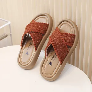 Primer plano de pantuflas para niñas con correas cruzadas de ganchillo y pompones