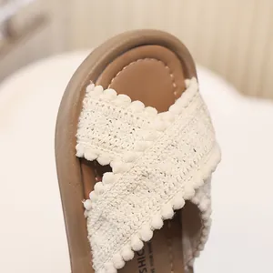 Primer plano de chanclas de ganchillo para niñas con correas cruzadas y pompones