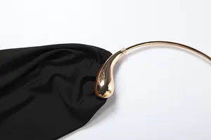 Detailed macro shot of golden water-drop shaped metallic neck ring on black halter top
