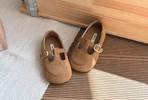 Dettaglio di scarpe T-strap vintage in camoscio marrone per bambina con fibbie in bronzo antico