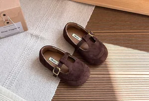 Primo piano di scarpe vintage in camoscio marrone con cinturino a T per bambini e suola morbida