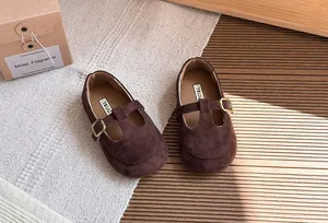 Dettaglio di scarpe vintage in camoscio marrone con cinturino a T per bambine con suola morbida