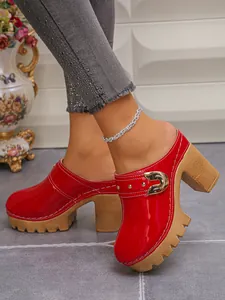 Side view detail of red patent leather platform clogs with chunky heels and rivets