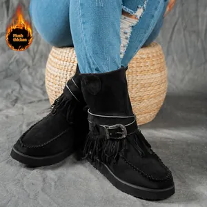 Close-up detail of black suede snow boots featuring fringe and metal buckle strap.