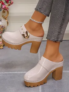 Close-up of beige patent leather high heel platform mules with gold buckle detail